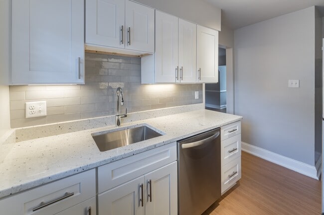 The Cary renovated kitchen with white cabinets, stainless steel appliances and a microwave - Malvern Manor Apartments