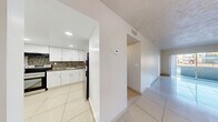 Located in Lauderhill, FL, this three-bedroom, one-bathroom residence offers a practical and well-organized single-floor layout. Gleaming large-format white tile flooring runs throughout the entire unit, creating a bright and cohesive look from room to room. The open combined living and dining area is generously proportioned, bathed in natural light from a sliding glass door that leads to a private balcony with outdoor views — a standout feature that enhances the sense of openness. The kitchen is well-appointed with white shaker-style cabinetry, dark granite-look countertops, a colorful mosaic tile backsplash, stainless steel appliances including a refrigerator and electric range, and recessed lighting. A hallway connects the main living areas to the three bedrooms, each featuring textured walls, tile flooring, and closets — with the primary bedroom offering a notably spacious footprint. The full bathroom includes a tub/shower combination with clean white tile surround. Additional highlights include four closets providing ample storage, a dedicated laundry area, and a textured ceiling detail visible throughout. The unit's neutral palette and tile flooring throughout make it a clean, move-in ready space.