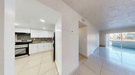 Located in Lauderhill, FL, this three-bedroom, one-bathroom residence offers a practical and well-organized single-floor layout. Gleaming large-format white tile flooring runs throughout the entire unit, creating a bright and cohesive look from room to room. The open combined living and dining area is generously proportioned, bathed in natural light from a sliding glass door that leads to a private balcony with outdoor views — a standout feature that enhances the sense of openness. The kitchen is well-appointed with white shaker-style cabinetry, dark granite-look countertops, a colorful mosaic tile backsplash, stainless steel appliances including a refrigerator and electric range, and recessed lighting. A hallway connects the main living areas to the three bedrooms, each featuring textured walls, tile flooring, and closets — with the primary bedroom offering a notably spacious footprint. The full bathroom includes a tub/shower combination with clean white tile surround. Additional highlights include four closets providing ample storage, a dedicated laundry area, and a textured ceiling detail visible throughout. The unit's neutral palette and tile flooring throughout make it a clean, move-in ready space.