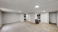 Located at 2030 Generals Way in Dover, Delaware, this single-floor unit offers a practical and well-designed layout across a compact but functional footprint. The main living area is an open, carpeted space finished in neutral gray tones with a textured ceiling and recessed flush lighting throughout. Windows fitted with blinds allow natural light to filter in, and a wall-mounted HVAC unit provides climate control. The flooring transitions from plush carpet in the living zone to wood-look vinyl planking in the kitchen and utility areas, creating a clear and clean delineation between spaces. The kitchen is efficiently designed in a galley-style configuration, featuring gray cabinetry, a light quartz countertop, a stainless steel sink with a pull-down faucet, and a full suite of stainless steel appliances including a refrigerator, dishwasher, electric range, and over-the-range microwave. An electrical panel is conveniently housed within the kitchen. A dedicated laundry area includes a stacked washer and dryer unit, adding significant convenience. The bathroom is clean and straightforward, featuring wood-look flooring, a tub and shower combination, and crisp white fixtures throughout. The overall aesthetic is modern, minimal, and move-in ready.
