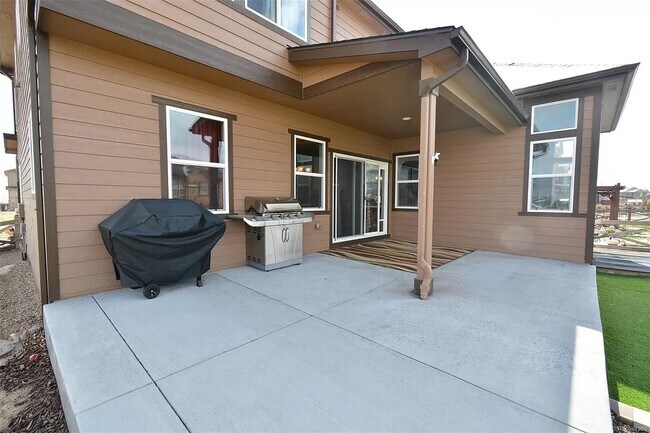 Terraza trasera con césped artificial y jardineras exteriores con rocas y flores. - 8782 Windy Plains Ct