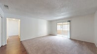 Located at 720 S Conway Rd in Orlando, Florida, this single-story residence offers a practical and comfortable layout with two bedrooms and two bathrooms. The open combined living and dining area is a centerpiece of the home, featuring plush carpet, warm wood-look flooring in the transition zones, a textured ceiling, and a sliding glass door that fills the space with natural light and provides access to an outdoor area. A hallway with wood-look flooring connects the main living space to the private quarters, keeping the layout organized and easy to navigate. The kitchen is well-equipped with white cabinetry, granite-style countertops, a double-basin sink, a dishwasher, a stainless steel refrigerator, and light tile flooring, along with a pantry for additional storage. Both bedrooms are carpeted and feature textured ceilings and closets, with the primary bedroom offering generous proportions and natural light from a window. The two bathrooms include a clean, tiled tub-shower combination. A dedicated utility room and multiple closets throughout the home provide abundant storage. The overall aesthetic is clean and neutral, with white walls and consistent finishes creating a bright, move-in ready atmosphere.