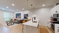 Located at 6505 Rockhill Rd in Kansas City, MO, this single-floor residence showcases a contemporary design with clean lines, neutral tones, and high-quality finishes throughout. The open-concept layout seamlessly connects the kitchen, dining, and living areas, creating a bright and cohesive living space.

The kitchen is a standout feature, outfitted with sleek white cabinetry extending to the ceiling, a navy tile backsplash, stainless steel appliances, and a generous white quartz island with an undermount sink and matte black faucet. Pendant lighting clusters above the island add a modern touch, while light wood-tone flooring runs throughout the main living areas, enhancing the airy atmosphere.

The living area offers a comfortable, well-lit setting with recessed lighting and a large window allowing natural light to fill the room. The bedroom features plush carpet flooring, generous natural light through wide windows with blinds, and ample space for furnishings. A second bedroom provides a similarly serene retreat.

The bathroom is finished with white cabinetry, matte black hardware, a clean vanity with quartz countertops, and light wood-tone flooring, maintaining the modern aesthetic found throughout the space. Overall, the unit delivers a polished, move-in-ready environment with thoughtful design details.