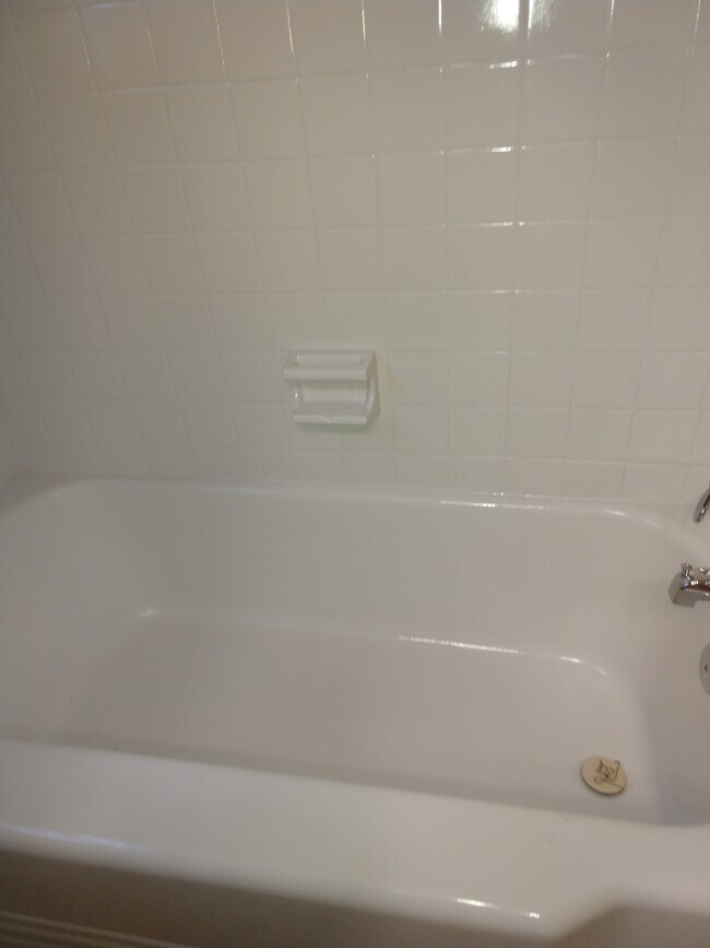 Newly resurfaced cast-iron tub with new faucets, surrounded by resurfaced ceramic tile, shower with new faucets - 4800 Matthews-Mint Hill Rd