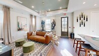 This 680 square foot clubhouse in Calabash, NC, combines functionality with modern design. The space is divided into three main areas: a fitness center, a lounge, and a kitchen. The exercise room is equipped with state-of-the-art fitness equipment, including cardio machines and strength training apparatus. A wall-mounted TV and beverage cooler provide entertainment and refreshment options during workouts.

The lounge area features a sophisticated design with a tray ceiling, chandelier lighting, and contemporary artwork. A comfortable leather sofa, accent chairs, and a stylish area rug create an inviting atmosphere for relaxation or socializing. Large windows allow natural light to flood the space, enhancing its open and airy feel.

The kitchen area, while compact, is efficiently designed with white cabinetry, dark green tiled backsplash, and stainless steel appliances. It includes a sink, refrigerator, and coffee station, making it perfect for preparing light refreshments or hosting small gatherings.

Throughout the clubhouse, hardwood flooring and recessed lighting contribute to the cohesive, modern aesthetic. The thoughtful layout and design elements make this space a versatile amenity for fitness enthusiasts and those seeking a comfortable area for leisure activities.