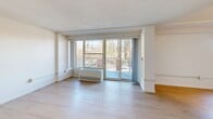 Located at 295 Harvard St in Cambridge, MA, this single-floor unit offers a well-organized layout comprising a living room and a full bathroom. Light-toned hardwood flooring runs throughout the main living areas, complementing the crisp white walls and creating a clean, modern aesthetic. The living room is a standout space, featuring large sliding glass doors and expansive windows that flood the room with natural light and provide views of the surrounding greenery and outdoor area. A textured ceiling adds subtle architectural character to the open living space. The kitchen is accessible directly from the living area and is equipped with white cabinetry, a peninsula counter, and stainless steel appliances, offering a functional and efficient cooking space. A narrow entry hallway with recessed lighting leads from the front door into the main living area, providing a smooth and defined transition. The bathroom is finished with large-format beige marble-style tiles covering both the floor and the full-height walk-in shower walls, lending a warm and polished look. A white vanity with clean-lined cabinetry and recessed overhead lighting complete the bathroom's refined finish. Overall, the space maintains a bright, neutral palette that maximizes the sense of openness throughout.