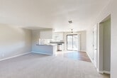 Located at 46745 Monroe St in Indio, California, this two-bedroom, two-bathroom single-floor residence offers a well-designed layout with a clean, neutral aesthetic throughout. The open-concept living area seamlessly connects the living room, dining space, and kitchen, creating a bright and cohesive gathering space. The kitchen features white cabinetry, a peninsula with a dark countertop, stainless steel appliances including a dishwasher, and wood-look flooring that extends into the kitchen and dining zone. A ceiling fan anchors the living area, which opens directly to a private balcony through sliding glass doors, allowing for natural light and outdoor views. Soft carpet covers the living room and both bedrooms, providing a comfortable feel underfoot. The spacious primary bedroom offers a dedicated closet with built-in hanging rods and a window for natural light. The second bedroom is equally well-proportioned with a large window and textured ceiling. Both bathrooms are fitted with clean white shower surrounds and chrome fixtures — one with a walk-in shower and the other with a shower-tub combination. A utility room and hallway round out the functional layout, making this a practical and comfortable home in the heart of the Coachella Valley.