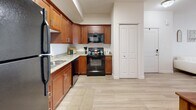 Located at 500 N Broadway in Farmington, Utah, this well-appointed one-bedroom, one-bathroom residence offers a thoughtfully designed single-level layout. Light wood-style flooring flows throughout the main living areas, creating a cohesive and clean aesthetic. The open-concept kitchen and living room form the heart of the home, with the kitchen showcasing rich warm-toned cabinetry, granite-style countertops, black appliances including a refrigerator, range, microwave, and dishwasher, and a skylight that draws in natural light. A dining area sits adjacent, providing a practical space for everyday meals. The living room is bright and welcoming, featuring large windows with views to the outdoors and direct access to a private patio. The bedroom offers a comfortable, carpet-floored retreat with a window allowing natural light and outdoor views. The full bathroom is finished with warm wood cabinetry, granite countertops, a combined tub and shower, and open shelving for storage. Two closets provide ample storage throughout the unit. A dedicated in-unit laundry room with full-size washer and dryer hookups adds everyday convenience. The overall ambiance is clean, modern, and functional, making excellent use of the available space.