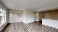 Located at 55 Woods in Hamden, Connecticut, this single-floor residence offers a clean, modern design with a neutral color palette and hardwood-style flooring throughout. The open-concept living area is bright and airy, benefiting from large windows that frame lush, wooded views and invite abundant natural light. Sliding glass doors lead to an outdoor deck, seamlessly connecting the interior to the natural surroundings.

The kitchen is well-equipped and features rich dark cabinetry with sleek hardware, granite-style countertops, stainless steel appliances including a range and refrigerator, and a peninsula that separates it from the main living space. Recessed lighting enhances the kitchen area, adding warmth to the darker cabinetry tones.

The bedroom is generously sized with a large window providing natural light and views of the adjacent exterior. The bathroom maintains the same consistent design language with a dark vanity topped with a white countertop, hardwood-style flooring, and a clean, minimalist finish. Additional doors throughout suggest ample closet and storage space. The overall ambiance is fresh, contemporary, and move-in ready, making this a well-designed residence in a peaceful, nature-adjacent setting.