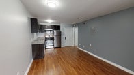 Located on Hollywood Boulevard in Los Angeles, this single-floor unit offers a clean and functional layout designed for comfortable urban living. Warm-toned hardwood flooring runs throughout the space, providing a cohesive and inviting feel across every room.

The kitchen is well-equipped and efficiently arranged in an L-shaped configuration. Dark espresso cabinetry extends from floor to ceiling, offering generous storage, while granite countertops add a refined finish. Stainless steel appliances — including a gas range, over-the-range microwave, refrigerator, and dishwasher — complete the kitchen's modern, practical setup. A tiled backsplash adds a subtle design detail behind the cooking area.

The open living and dining area is spacious and bright, with cool gray walls that complement the hardwood floors. A sliding door with vertical blinds allows natural light to filter in from outside. The room provides ample space for flexible furniture arrangements and includes a wall-mounted utility panel.

The bedroom is a quiet, well-proportioned room featuring a window with natural light and a wall-mounted mini-split air conditioning unit for individual climate control.

The bathroom features a vanity with a white countertop sink and dark cabinetry, finished with the same cool gray tones found throughout the unit. A connecting hallway provides easy access between the bathroom, bedroom, and main living areas, creating a smooth and logical flow through the space.