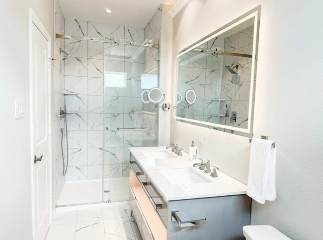 Bathroom with double sinks, backlit mirror, and standing shower - West End Estates