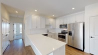 Located at 1520 S Missouri Ave in Morton, Illinois, this single-floor unit offers a thoughtfully designed layout with contemporary finishes throughout. The open-concept kitchen serves as a central highlight, featuring crisp white shaker-style cabinetry extending to the ceiling for ample storage, bright quartz countertops, and a large island ideal for additional prep space or casual dining. Stainless steel appliances — including a refrigerator with ice maker, range, built-in microwave, and dishwasher — complement the space, while a matte black faucet adds a modern contrast. A white tile backsplash and recessed lighting complete the kitchen's clean aesthetic.

The living area flows naturally from the kitchen, benefiting from natural light streaming through a sliding door and windows, highlighting the warm-toned hardwood-style flooring that extends throughout the main living spaces. Bedrooms feature plush carpeting, generous closet space with sliding doors, and a calm, neutral palette. Two bathrooms are finished with white vanities, light tile flooring, and matte black hardware and fixtures — one featuring a full tub/shower combination. The overall design is clean, modern, and move-in ready.