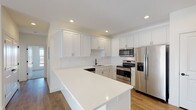 Located at 1520 S Missouri Ave in Morton, Illinois, this single-floor unit offers a thoughtfully designed layout with contemporary finishes throughout. The open-concept kitchen serves as a central highlight, featuring crisp white shaker-style cabinetry extending to the ceiling for ample storage, bright quartz countertops, and a large island ideal for additional prep space or casual dining. Stainless steel appliances — including a refrigerator with ice maker, range, built-in microwave, and dishwasher — complement the space, while a matte black faucet adds a modern contrast. A white tile backsplash and recessed lighting complete the kitchen's clean aesthetic.

The living area flows naturally from the kitchen, benefiting from natural light streaming through a sliding door and windows, highlighting the warm-toned hardwood-style flooring that extends throughout the main living spaces. Bedrooms feature plush carpeting, generous closet space with sliding doors, and a calm, neutral palette. Two bathrooms are finished with white vanities, light tile flooring, and matte black hardware and fixtures — one featuring a full tub/shower combination. The overall design is clean, modern, and move-in ready.