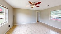 Located at 2215 Buffalo Trail in Morristown, Tennessee, this single-story home offers a practical and well-organized layout comprising one bedroom, two bathrooms, a living room, kitchen, hallway, closet, and a dedicated utility room. Light-toned ceramic tile flooring is consistent throughout the main living areas, contributing to a clean and cohesive aesthetic. The spacious living room is bright and open, featuring a ceiling fan with light fixture and a window that allows natural light to filter in. A built-in closet with louvered bifold doors provides convenient storage directly off the living area. The bedroom is a comfortable size, equipped with its own ceiling fan, a window with outdoor views, and a double-door closet offering ample storage. The kitchen is efficiently designed with white cabinetry extending to the ceiling for generous storage, light wood-look flooring, a stainless steel sink, and appliances including a refrigerator and range. Both bathrooms feature white square tile wainscoting and a clean, utilitarian finish, with one bathroom including a bathtub and window for natural ventilation. Ceiling fans are present throughout the home, enhancing comfort year-round.
