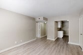 Located at 1900 Delowe Stanton Rd in East Point, GA, this single-floor, one-bedroom, one-bathroom unit offers a practical and well-organized layout. The living area greets you at the entrance, featuring light wood-style flooring, neutral taupe walls, and a textured ceiling, creating a clean and understated aesthetic. A window near the front door allows natural light to fill the space.

The kitchen is positioned adjacent to the living area and is outfitted with white shaker-style cabinetry, gray countertops, and black appliances including a refrigerator and electric range with an overhead exhaust hood. The wood-style flooring continues seamlessly into the kitchen, maintaining a cohesive look throughout.

A hallway connects the main living area to the bedroom and bathroom. The bedroom offers a comfortable footprint, carpeted flooring for added warmth, a window with natural light, and a bi-fold closet for storage. The full bathroom features a white vanity with cabinet storage, a mirror, a toilet, and a shower-tub combination with a window above, providing natural ventilation and light. The overall palette of whites and warm neutrals gives the unit a clean, move-in-ready feel.