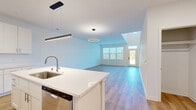 This well-designed two-story home offers 2 bedrooms and 3 bathrooms across two thoughtfully laid-out floors. The main level features an open-concept living and kitchen area with soaring vaulted ceilings and a striking circular pendant light fixture that anchors the living space. Large windows and a glass-paneled front door flood the area with natural light, while light-toned hardwood-style flooring runs throughout the lower level. The kitchen is a standout feature, outfitted with crisp white shaker cabinetry, white quartz countertops, a large center island with an undermount sink, and a full suite of stainless steel appliances including a refrigerator, range, microwave, and dishwasher. A dedicated walk-in pantry provides generous storage. A convenient half bathroom is also located on the main floor. Upstairs, the primary bedroom offers a comfortable retreat with plush carpeting and a spacious en-suite bathroom featuring a dual-sink vanity with quartz countertops and a walk-in shower. The second bedroom is well-sized with soft carpet, a large closet, and a wide window showcasing open outdoor views. A staircase connects both floors, and hallways on each level ensure a smooth, functional flow throughout the home.