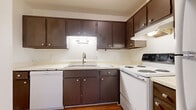 This single-floor, 2-bedroom, 1-bathroom unit features a practical and well-organized layout designed for comfortable everyday living. The living area is generously proportioned, finished with neutral-toned carpet and fitted with a ceiling fan. Multiple windows dressed with vertical blinds allow ample natural light to fill the space, creating a bright and airy atmosphere.

The kitchen is efficiently arranged in an L-shaped configuration, featuring dark espresso-toned cabinetry that provides substantial storage space. White appliances — including an electric range, dishwasher, and range hood — complement the light countertops, while warm hardwood-style flooring adds a welcoming touch underfoot.

Both bedrooms are comfortably sized and carpeted, each with windows that bring in natural light and views of the surrounding exterior. One bedroom includes a mirrored sliding closet door, offering convenient storage, while the other features two dark-panel doors leading to a closet and the hallway.

The bathroom is clean and straightforward, with a tub-shower combination, a vanity with matching dark cabinetry, and hardwood-style flooring that ties in cohesively with the kitchen. Throughout the unit, the neutral color palette and consistent finishes create a calm, move-in ready environment suited to a variety of lifestyles.