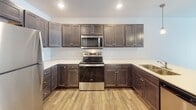 Located at 6300 S Tallgrass Ave in Sioux Falls, SD, this single-floor unit offers a thoughtfully organized layout with a clean, neutral aesthetic throughout. The kitchen serves as a functional centerpiece, featuring rich dark-stained cabinetry with ample upper and lower storage, light-toned countertops, stainless steel appliances including a refrigerator, electric range, and over-the-range microwave, and durable wood-look flooring that extends through the common areas.

Multiple bedrooms provide comfortable living spaces, each finished with plush neutral carpet, white-trimmed windows fitted with blinds for natural light control, and ceiling-mounted light fixtures. One bedroom includes a private en-suite bathroom, adding a convenient level of privacy.

The unit includes two bathrooms: one featuring a full tub-shower combination with a curved curtain rod and grab bar, and another with a standalone shower stall, both finished with wood-look flooring and dark-toned vanities with white countertops.

A dedicated in-unit laundry closet houses a full-sized top-loading washer and dryer behind sliding panel doors, providing added convenience. Overall, the space presents a clean, move-in ready environment with consistent finishes and practical amenities throughout.