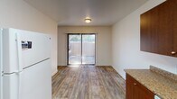 Located at 45418 Howe Rd in San Diego, this two-story residence offers a functional and well-organized layout across two levels connected by a staircase with a handrail. The main level features wood-style plank flooring throughout the living and dining areas, creating a warm and cohesive aesthetic. A sliding glass door in the living/dining area floods the space with natural light and provides direct access to an outdoor patio, bringing in views of surrounding greenery. The kitchen is well-appointed with rich wood cabinetry, granite-style countertops, a gas range, a full-size refrigerator, and a dishwasher, all set atop matching wood-style flooring. A half bathroom on the main level includes a granite-topped vanity with a dual-mirror setup. Upstairs, carpeted bedrooms provide a comfortable retreat, each featuring windows with vertical blinds that allow natural light while maintaining privacy. The upper-level full bathroom is equipped with a tub-shower combination and a window for natural ventilation. The stairwell itself is accented by a window landing that introduces additional natural light. Throughout, the interior is finished with textured walls and neutral tones, contributing to a clean and move-in-ready atmosphere.