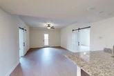 Located in Liverpool, NY, this well-appointed 2-bedroom, 3-bathroom residence offers a thoughtfully designed single-floor layout. The open-concept living and kitchen area serves as the heart of the home, featuring durable wood-style flooring, a ceiling fan, and striking sliding barn doors that add a modern farmhouse touch. The kitchen is outfitted with dark espresso cabinetry, stainless steel appliances, and a generous granite-topped peninsula with an undermount sink — ideal for both cooking and casual dining.

The spacious primary bedroom is carpeted for comfort and includes a ceiling fan, a walk-in closet with wire shelving, and an en-suite bathroom complete with a granite vanity, dark wood cabinetry, and a tub-shower combination with sliding glass doors. The second bedroom is equally well-lit, featuring dual windows that invite abundant natural light and a ceiling fan overhead.

A private balcony with metal railing provides a standout outdoor feature, offering sweeping views of the water and a historic truss bridge — a picturesque backdrop that elevates the overall living experience. With two dedicated closets, clean neutral finishes throughout, and a bright, airy ambiance, this residence blends functionality with contemporary style.