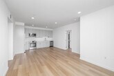 Located at 1233 S Dunsmuir Ave in Los Angeles, this modern 2-bedroom, 2-bathroom residence offers a clean, minimalist aesthetic across a single thoughtfully designed floor. Light oak hardwood flooring runs throughout, complementing the crisp white walls and creating a bright, cohesive atmosphere in every room.

The open-concept kitchen and living area serves as the heart of the home, featuring stainless steel appliances including a range, over-the-range microwave, and dishwasher, paired with sleek gray cabinetry and light countertops. A hallway connects the living spaces to the private quarters, equipped with a smart thermostat for convenient climate control.

The primary bedroom is a generous retreat with sliding glass doors opening onto a private balcony, offering outdoor views of the surrounding neighborhood and filling the space with natural light. The second bedroom also benefits from natural light through a large window with neighborhood views. Each bedroom includes dedicated closet space.

Both bathrooms continue the modern design language, featuring glass-enclosed walk-in showers, clean-lined vanities, and wood-tone flooring. An in-unit laundry area adds everyday convenience. The overall ambiance is open, airy, and contemporary, making this a well-appointed urban residence.