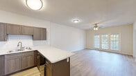 Located at 4636 Canterbury Dr in Myrtle Beach, SC, this single-floor residence offers a thoughtfully designed open-concept layout that seamlessly connects the kitchen and living area. The kitchen is well-appointed with dark taupe cabinetry, light quartz countertops, a subway tile backsplash, a central island with additional storage, and black stainless Whirlpool appliances including a refrigerator, electric range, and over-the-range microwave. Light wood-look flooring extends throughout the main living spaces, complementing the bright, neutral palette of the walls. The spacious living area is anchored by a ceiling fan and features French doors that invite natural light and provide access to the outdoors. The bedrooms are generously sized, each equipped with ceiling fans and plush neutral carpeting, creating a comfortable and airy atmosphere. The bathroom includes a tub-shower combination with a built-in surround, a dark wood vanity with a white countertop, and wood-look flooring that ties in with the rest of the home. Clean white walls and consistent finishes throughout give this single-level home a cohesive, move-in-ready appeal.