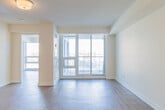Located at 420 Harwood Avenue South in Ajax, Ontario, this one-bedroom, one-bathroom unit offers a well-designed layout across a single floor. Light-toned laminate flooring runs continuously throughout the space, creating a cohesive and clean aesthetic.

The open-concept kitchen and living area forms the heart of the unit. The kitchen is equipped with rich dark-brown cabinetry extending to the ceiling, light granite-style countertops, stainless steel appliances including a refrigerator and range, a built-in range hood, and a stainless steel sink. The layout provides ample storage and counter workspace.

The living area is notably bright, featuring floor-to-ceiling windows and a sliding glass door that opens to a private balcony with views of the surrounding Ajax neighbourhood. Natural light fills the room throughout the day, enhancing the open and airy feel of the space.

The primary bedroom is a well-proportioned room with light walls and laminate flooring, offering access to a dedicated closet with sliding doors. A hallway with additional closet storage connects the main living areas to the bedroom and bathroom.

The bathroom is finished with clean white tile surrounding a full soaking tub and shower combination, complemented by chrome fixtures. The overall design of the unit is modern and functional, suited for comfortable everyday living.