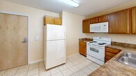 This 2-bedroom, 2-bathroom residence at 82 Jerome Rd in Uncasville, CT offers a well-organized single-floor layout designed for comfortable everyday living. The kitchen is equipped with warm-toned wooden cabinetry, granite-style countertops, white appliances including a refrigerator, electric range, microwave, and dishwasher, and is finished with light ceramic tile flooring. A peninsula with a pendant chandelier overhead opens the kitchen toward the living area, which features plush carpeting and a window that brings in natural light and outdoor greenery views. Both bedrooms are carpeted and finished with neutral, warm beige walls. The primary bedroom includes a closet and direct access to its own bathroom, which features a warm wood vanity with a single sink, tile flooring, and a full shower-tub combination. The second bedroom also benefits from natural light via a window with outdoor views, and is served by a second bathroom finished with matching tile flooring and a tub-shower combo. Throughout the residence, clean white trim and soft neutral wall tones create a cohesive, understated aesthetic. Wall-mounted HVAC units are present in the main living and bedroom areas, providing individual climate control.