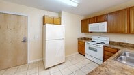 This 2-bedroom, 2-bathroom residence at 82 Jerome Rd in Uncasville, CT offers a well-organized single-floor layout designed for comfortable everyday living. The kitchen is equipped with warm-toned wooden cabinetry, granite-style countertops, white appliances including a refrigerator, electric range, microwave, and dishwasher, and is finished with light ceramic tile flooring. A peninsula with a pendant chandelier overhead opens the kitchen toward the living area, which features plush carpeting and a window that brings in natural light and outdoor greenery views. Both bedrooms are carpeted and finished with neutral, warm beige walls. The primary bedroom includes a closet and direct access to its own bathroom, which features a warm wood vanity with a single sink, tile flooring, and a full shower-tub combination. The second bedroom also benefits from natural light via a window with outdoor views, and is served by a second bathroom finished with matching tile flooring and a tub-shower combo. Throughout the residence, clean white trim and soft neutral wall tones create a cohesive, understated aesthetic. Wall-mounted HVAC units are present in the main living and bedroom areas, providing individual climate control.