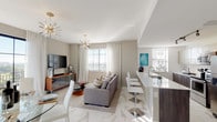 This well-appointed single-floor residence showcases a thoughtfully designed open-concept layout that seamlessly connects the main living areas. The entryway sets an elegant tone with marble-look porcelain tile flooring that extends throughout the unit, warm taupe walls, and striking sculptural metallic wall art on both sides of the entry corridor.

The living area is bathed in natural light from large windows and a floor-to-ceiling sliding glass door that opens to a private balcony, offering sweeping views of the surrounding cityscape and waterway. A sputnik-style chandelier adds a contemporary focal point overhead, while the space flows naturally into a dedicated dining area.

The kitchen features stainless steel appliances, a full-size side-by-side refrigerator, modern two-tone cabinetry, and white quartz countertops. A peninsula with bar seating provides a practical connection to the living space.

The bedroom is a serene retreat, finished with soft neutral tones, dual windows dressed in sheer mauve curtains, and a dedicated closet. A glass-panel partition subtly defines spaces while maintaining an open, airy feel throughout. Colorful abstract artwork and carefully selected furnishings contribute to the residence's cohesive contemporary aesthetic.