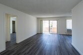Located at 1025 S Holt Ave in the heart of Los Angeles, CA, this thoughtfully renovated single-floor residence combines contemporary finishes with a clean, functional layout. The galley-style kitchen is a standout feature, showcasing white shaker cabinetry, quartz countertops with elegant veining, a classic subway tile backsplash, stainless steel appliances including a refrigerator, range, microwave, and dishwasher, and a deep double-basin sink with a modern pull-down faucet. Light wood-style flooring flows seamlessly throughout the unit, lending warmth and cohesion to every room. The spacious living area is bright and airy, filled with natural light from large windows fitted with vertical blinds and a sliding glass door that opens to a private balcony. A ceiling fan adds comfort to the living space, which also features a wall-mounted AC unit. The bathrooms have been updated with marble-look quartz countertops, vessel or undermount sinks, brushed nickel and matte black fixtures, and large framed mirrors. The overall aesthetic is fresh and neutral, with white walls and textured ceilings creating a versatile canvas throughout this well-appointed Los Angeles residence.