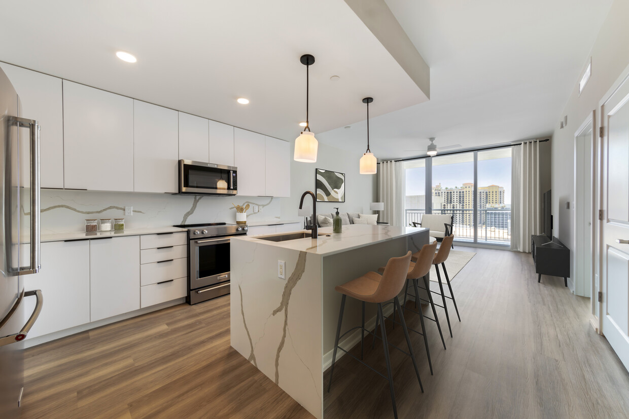 Tower Building - Renovated kitchen with stainless steel appliances, marbled white quartz countertops, light grey cabinetry, and hard surface flooring - Avalon West Palm Beach