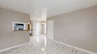 Located at 8600 S Course Dr in Houston, TX, this 2-bedroom, 2-bathroom unit offers a practical and well-organized single-floor layout. The living and dining areas flow seamlessly together, finished with gleaming marble-look porcelain tile flooring that extends throughout the main living spaces. Natural light enters through windows and a glass-paned front door, while a chandelier accent light adds a touch of warmth to the dining area. A pass-through window connects the dining space to the galley-style kitchen, which is outfitted with granite countertops, a double sink, gray cabinetry, and stainless steel appliances including a refrigerator and electric range. The kitchen also provides direct access to one of the bathrooms. Both bedrooms feature plush carpet flooring and ceiling fans with lighting, along with windows that bring in natural light. The primary bedroom includes a walk-in closet with built-in wire shelving, offering generous storage. The two bathrooms are finished with the same marble-look tile and include granite-topped vanities with gray cabinetry. One bathroom features a tub-shower combination with clean white tile surround. Three closets throughout the unit provide ample storage for everyday needs.