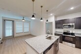 Located at 6131 Louetta Road in Spring, TX, this two-bedroom, two-bathroom unit offers a well-designed single-floor layout that maximizes functionality. The kitchen serves as the centerpiece, featuring dark espresso-toned shaker cabinetry, granite countertops, stainless steel appliances including a full-size refrigerator and range, and a peninsula with pendant lighting and an undermount sink — ideal for both cooking and casual dining. Light wood-style flooring flows through the main living and kitchen areas, creating a clean, contemporary aesthetic.

Both bedrooms are carpeted and bathed in natural light through slatted blinds, each equipped with a ceiling fan for year-round comfort. The primary bedroom includes access to a dedicated closet, offering practical storage. Each bedroom benefits from a well-appointed bathroom. One bathroom features a tub-shower combo with white subway tile surround, while the other includes a vanity with granite countertops and dark cabinetry that mirrors the kitchen's design language. The overall palette of crisp white walls, dark fixtures, and stone-toned surfaces creates a cohesive, modern interior throughout the unit.