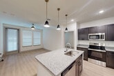 Located at 6131 Louetta Road in Spring, TX, this two-bedroom, two-bathroom unit offers a well-designed single-floor layout that maximizes functionality. The kitchen serves as the centerpiece, featuring dark espresso-toned shaker cabinetry, granite countertops, stainless steel appliances including a full-size refrigerator and range, and a peninsula with pendant lighting and an undermount sink — ideal for both cooking and casual dining. Light wood-style flooring flows through the main living and kitchen areas, creating a clean, contemporary aesthetic.

Both bedrooms are carpeted and bathed in natural light through slatted blinds, each equipped with a ceiling fan for year-round comfort. The primary bedroom includes access to a dedicated closet, offering practical storage. Each bedroom benefits from a well-appointed bathroom. One bathroom features a tub-shower combo with white subway tile surround, while the other includes a vanity with granite countertops and dark cabinetry that mirrors the kitchen's design language. The overall palette of crisp white walls, dark fixtures, and stone-toned surfaces creates a cohesive, modern interior throughout the unit.