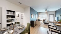 This thoughtfully designed 2-bedroom, 2-bathroom residence spans a single floor and offers a cohesive blend of modern style and functional living. The open-concept layout seamlessly connects the kitchen, dining area, and living room, creating a welcoming, communal atmosphere. The kitchen features white shaker cabinetry, stainless steel appliances, dark countertops, a peninsula with pendant lighting, and light wood-style flooring that carries throughout the home. The living room is anchored by a bold teal accent wall, ceiling fan, and large windows that invite abundant natural light. A dedicated dining area completes the social hub of the home. The primary bedroom is generously sized, highlighted by deep teal walls, a ceiling fan, and ample natural light. Its en-suite bathroom features a glass-enclosed walk-in shower with dramatic dark marble tile surround and a dual-sink vanity. The second bedroom showcases a striking floral wallpapered accent wall and bright windows. The second bathroom offers a full tub-shower combination with clean white tile finishes. Two closets and a hallway provide additional storage and connectivity throughout the residence.
