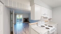 Located in Spokane Valley, WA, this efficiently designed one-bedroom, one-bathroom unit offers a thoughtful layout across a single floor. The open-concept living, dining, and kitchen area serves as the heart of the home, creating a seamless flow between spaces. The living room is highlighted by a charming stone fireplace and a sliding glass door that fills the room with natural light and provides direct access to the outdoor patio area, which features river rock landscaping along the building exterior.

The galley-style kitchen is outfitted with crisp white shaker cabinetry, marble-look countertops, and white appliances including a range, dishwasher, and refrigerator. Blue vertical pinstripe accent tiles add a subtle decorative touch that ties the kitchen and living area together.

The bedroom is a comfortable, well-proportioned retreat featuring light-toned hardwood-style flooring, neutral walls, a bright window with a view of the surrounding greenery, and a baseboard heater. A dedicated closet provides practical storage.

The bathroom is clean and functional, featuring a full tub-shower combination, a white vanity, and matching hardwood-style flooring consistent with the rest of the unit. Throughout the space, light wood-tone flooring unifies each room, contributing to a bright, cohesive, and welcoming ambiance.
