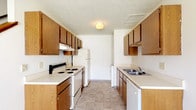 Located at 2960 Abbots Cove Blvd in Columbus, Ohio, this two-floor residence offers a practical and functional layout spread across two levels. The galley-style kitchen is efficiently designed with wood-toned cabinetry lining both walls, providing ample upper and lower storage. White appliances — including an electric range, refrigerator, and dishwasher — complement the light countertops, while tile flooring and a textured ceiling complete the space. A dedicated laundry area is accessible directly from the kitchen. The full bathroom features a single-sink vanity with a large mirror, a combination tub and shower, and tile flooring, maintaining a clean and neutral aesthetic throughout. The living area on the main level is carpeted and benefits from natural light through a window, with a wall-mounted air conditioning unit and baseboard heating ensuring year-round comfort. A staircase connects the two floors. The upper level hosts carpeted bedrooms, each featuring baseboard heating and wood-trimmed doors. One bedroom includes a ceiling fan with light fixture and a window overlooking the exterior. Textured ceilings are consistent throughout the home, and warm wood baseboards provide a cohesive finish across all rooms.
