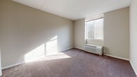 Located at 400 Foulk Rd in Wilmington, Delaware, this single-floor residence offers a well-organized layout designed for comfortable everyday living. The living area is generously sized, finished with wall-to-wall carpeting and neutral-toned walls that create a bright, welcoming atmosphere. Natural light filters in through windows equipped with a wall-mounted HVAC unit, ensuring year-round climate comfort. A striking feature of the space is a full wall of floor-to-ceiling mirrored panels, which visually expands the room and amplifies incoming light. The kitchen is outfitted with light wood cabinetry, dark countertops, a stainless steel backsplash, and a built-in dishwasher, offering both style and functionality. The bedrooms are carpeted and spacious, each featuring dedicated closet space — including walk-in and bi-fold closet configurations with built-in shelving for organized storage. A hallway with mirrored sliding closet doors connects the main areas, with additional built-in shelving visible nearby. Two bathrooms serve the unit, both finished with light tile flooring. One includes a vanity with white cabinetry and a mirror above, while the other features a clean, minimalist design with a white vanity and towel bar.