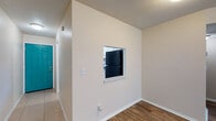 Located at 4300 18th St W in Bradenton, Florida, this single-story residence offers a practical and well-organized layout designed for comfortable everyday living. The kitchen is equipped with white cabinetry, a black appliance suite including a range and refrigerator, light tile flooring, and a pass-through window that connects to the dining and living areas, promoting an open and interactive flow between spaces. The living and dining areas feature warm wood-look plank flooring and neutral wall tones, creating a cohesive and inviting atmosphere throughout. A textured ceiling is present in several areas of the home. The bedrooms are carpeted for added comfort and include natural light from windows with blinds. At least one bedroom features a dedicated closet with bifold louvered doors, providing practical storage. A central hallway connects the main living spaces to the private areas of the home. The entry is marked by a distinctive teal door, adding a pop of color to the overall neutral palette. With consistent finishes, a straightforward floor plan, and convenient access throughout, this residence in Bradenton offers a functional and livable environment suited to a variety of needs.