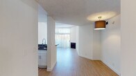 Located at 130 S Alexandria Ave in the heart of Los Angeles, this single-floor unit offers a bright and functional layout finished with light wood flooring and crisp white walls throughout. The open living area connects to a dedicated dining space and features a fireplace, with natural light streaming in through large windows fitted with vertical blinds. The kitchen is equipped with white shaker-style cabinetry, granite-look countertops, a stainless steel gas range, over-the-range microwave, and a refrigerator. A peninsula counter provides a convenient pass-through to the living and dining areas. The bedrooms are well-proportioned, each featuring light wood flooring, textured ceilings, and windows that allow for natural light. One bedroom includes a spacious sliding-door closet with built-in shelving. Two bathrooms serve the unit: one with a full tub-shower combination and a white vanity with stone-look countertop, and a second with a glass sliding-door shower enclosure and matching white cabinetry. The consistent use of neutral tones, updated fixtures, and wood-look flooring throughout gives the space a clean, modern aesthetic well-suited to urban Los Angeles living.