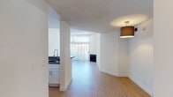 Located at 130 S Alexandria Ave in the heart of Los Angeles, this single-floor unit offers a bright and functional layout finished with light wood flooring and crisp white walls throughout. The open living area connects to a dedicated dining space and features a fireplace, with natural light streaming in through large windows fitted with vertical blinds. The kitchen is equipped with white shaker-style cabinetry, granite-look countertops, a stainless steel gas range, over-the-range microwave, and a refrigerator. A peninsula counter provides a convenient pass-through to the living and dining areas. The bedrooms are well-proportioned, each featuring light wood flooring, textured ceilings, and windows that allow for natural light. One bedroom includes a spacious sliding-door closet with built-in shelving. Two bathrooms serve the unit: one with a full tub-shower combination and a white vanity with stone-look countertop, and a second with a glass sliding-door shower enclosure and matching white cabinetry. The consistent use of neutral tones, updated fixtures, and wood-look flooring throughout gives the space a clean, modern aesthetic well-suited to urban Los Angeles living.