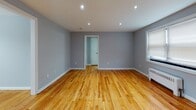 Located at 109 Hammell Place in Maywood, NJ, this single-floor unit presents a well-maintained interior with consistent design choices throughout. Warm hardwood flooring extends across the living areas and bedrooms, complemented by cool gray-toned walls and crisp white trim that create a clean, cohesive aesthetic.

The living area is generously proportioned, featuring recessed lighting, a large window that allows natural light to fill the space, and a front entry door with a transom window. A radiator provides heating, consistent with the other rooms. An adjacent dining area includes a pendant light fixture and additional window with natural light.

The kitchen has been thoughtfully updated with two-tone cabinetry — white upper cabinets paired with dark lower cabinets — white subway tile backsplash, light quartz countertops, and stainless steel appliances including a refrigerator, dishwasher, and range.

The bathroom features large-format wall tiles surrounding the soaking tub and shower, light porcelain floor tile, a dark vanity with a white countertop, an oval mirror, and natural light from two windows.

Additional rooms include well-sized bedrooms with hardwood floors, radiator heating, and windows providing natural light, offering versatile and functional living spaces throughout.