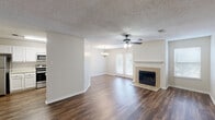 Located at 7827 N Jefferson Place Cir in Baton Rouge, Louisiana, this two-story home offers four bedrooms and three bathrooms across a well-organized layout. The main floor provides the bulk of the living space, beginning with an open living room highlighted by a tile-surround fireplace, a ceiling fan, and French doors that invite natural light. The adjacent dining area features an elegant chandelier and a pass-through connection to the kitchen, which is equipped with white cabinetry, light stone countertops, a subway tile backsplash, and stainless steel appliances. Rich hardwood-style flooring flows consistently throughout the main level, complementing the neutral wall tones and textured ceilings. A carpeted staircase with white balustrades leads to the upper floor, where the bedrooms are situated. The generously sized primary bedroom includes a ceiling fan, ample natural light from multiple windows, and access to a walk-in closet fitted with wire shelving. The primary bathroom features dual sinks set in a white vanity with abundant counter space. Additional bedrooms are carpeted and bright, each with window treatments. Throughout the home, a clean, neutral palette and consistent finishes create a cohesive and comfortable living environment.