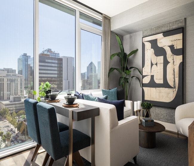 Interior de apartamento moderno con elegante comedor, cómodos asientos y vistas panorámicas de la ciudad a través de grandes ventanales. - Ancora