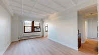 Located on the sixth floor at 1211 North La Salle Drive in Chicago's vibrant Near North Side, this one-bedroom, one-bathroom unit offers a well-designed layout across a single floor. The combined dining and living area serves as the heart of the home, showcasing distinctive coffered ceilings and light-toned hardwood flooring that carry throughout the space, creating a cohesive and airy feel. Natural light filters in through wood-framed windows, complemented by baseboard heating and a wall A/C unit. An elegant arched doorway adds a classic architectural touch to the open living area. The kitchen is efficiently laid out with white cabinetry, stainless steel appliances including a refrigerator and electric range, and striking marble-look quartz countertops and backsplash. The spacious bedroom features the same coffered ceiling detail, a large window with outdoor views, and access to multiple closets providing generous storage. The bathroom is finished with a walnut vanity, gold-toned fixtures, a subway-tiled tub/shower surround, and marble-look tile flooring. In-unit laundry adds everyday convenience, rounding out this thoughtfully appointed Chicago home.