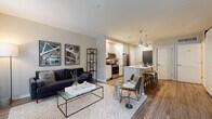 Located at 30 W First Ave in Columbus, Ohio, this contemporary single-floor residence offers a thoughtfully designed open-concept layout with modern finishes throughout. The living area is bright and welcoming, featuring large windows that flood the space with natural light and offer views of the surrounding neighborhood. A private door leads to an outdoor balcony, seamlessly blending indoor and outdoor living. Wood-style flooring runs throughout the main living areas, adding warmth and continuity to the design.

The kitchen is a standout feature, outfitted with white shaker cabinetry, a large center island with bar seating, stainless steel appliances, and stylish pendant lighting overhead — ideal for both everyday cooking and entertaining. The kitchen opens directly to the living and dining areas, reinforcing the spacious, connected feel of the floor plan.

The bedroom is generously sized with large windows providing ample natural light and views of greenery outside. A barn-style sliding door adds a distinctive architectural touch near the bedroom corridor.

The bathroom is clean and well-appointed, featuring a white vanity with ample storage, a tiled walk-in shower with glass enclosure, and light tile flooring. The overall ambiance of the residence is modern, airy, and functional, making it an excellent fit for urban living in Columbus.