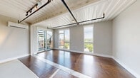 Located at 2150 Byrum Ave in Nashville, TN, this one-bedroom unit offers a distinctive industrial-chic aesthetic rooted in its repurposed shipping container architecture. The corrugated metal ceiling panels, exposed structural elements, and rich hardwood flooring create a raw yet refined character throughout the living space.

The open-plan kitchen is well-appointed with a full suite of stainless steel appliances, including a French door refrigerator, electric range, built-in microwave, and dishwasher. White cabinetry is complemented by open metal shelving, providing both style and functionality. A wall-mounted mini-split system ensures climate control throughout the unit.

The bedroom features neutral gray walls, dark hardwood flooring, and a tall window that frames lush greenery and open sky views, filling the room with natural light. A dedicated mini-split unit keeps the room comfortable year-round.

The living area includes generous closet storage and a conveniently located in-unit laundry alcove. Industrial-style track lighting overhead enhances the contemporary feel of the space.

A standout feature is the expansive rooftop deck, accessible from the unit, offering sweeping views of the Nashville skyline and surrounding treetops. The deck is finished with composite decking, black metal railings, and a built-in outdoor media cabinet, making it an exceptional outdoor entertaining space.