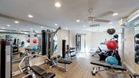 This fitness center offers a comprehensive workout environment designed to accommodate a wide range of exercise needs. The space features light-toned hardwood-style flooring and neutral walls that create a clean, welcoming atmosphere. Recessed lighting throughout the ceiling ensures the room is well-lit, while a ceiling fan provides comfortable air circulation during workouts.

The strength training area is anchored by multiple cable and weight machines, including cable crossover systems and multi-function weight stations suited for a variety of resistance exercises. Adjustable benches are positioned throughout the floor for use with the machines and free weights. Exercise balls in multiple sizes add versatility for core and balance training.

The cardio section includes treadmills and other aerobic equipment, providing options for both low- and high-intensity cardiovascular workouts. A large mirror spans one wall, creating the illusion of even greater space while allowing users to monitor their form.

The open layout ensures easy movement between equipment zones, and the overall design prioritizes functionality without sacrificing comfort. The bright, airy environment — supported by natural light and thoughtful overhead lighting — makes this fitness center an inviting and practical space for daily exercise routines.