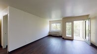 Located at 194 Tompkins Ave in Beacon, NY, this single-floor unit offers a clean, functional layout complemented by rich dark hardwood flooring that runs throughout the space. The living area is generously proportioned, bathed in natural light through large windows and a glass balcony door that opens to views of surrounding greenery, creating a bright and airy atmosphere. A wall-mounted HVAC unit and baseboard heating ensure year-round comfort. The open sightline from the living area extends toward a compact, well-organized kitchen, which features warm honey-toned wood cabinetry, ample upper and lower storage, a double-basin sink, an electric range, and a full-size refrigerator. A dedicated bedroom provides a peaceful retreat, with a window framing leafy outdoor views and a baseboard heater along the wall. Closet storage is also available within the unit. The bathroom is neatly appointed with a white vanity, mirrored medicine cabinet, a full soaking tub with shower, and chrome fixtures throughout. The overall aesthetic is understated and practical, with neutral cream-toned walls and dark flooring creating a cohesive, easy-to-customize interior. The unit's location in Beacon, NY, places it within reach of the Hudson Valley's arts, dining, and waterfront attractions.